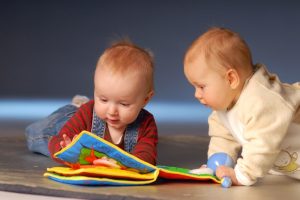 two babies looking a book. image for blooming babies story time post. 