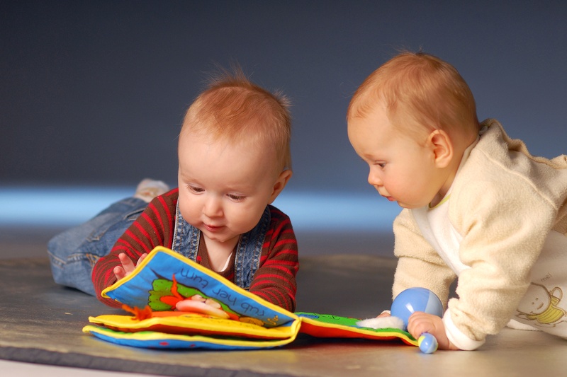 two babies looking a book. image for blooming babies story time post.